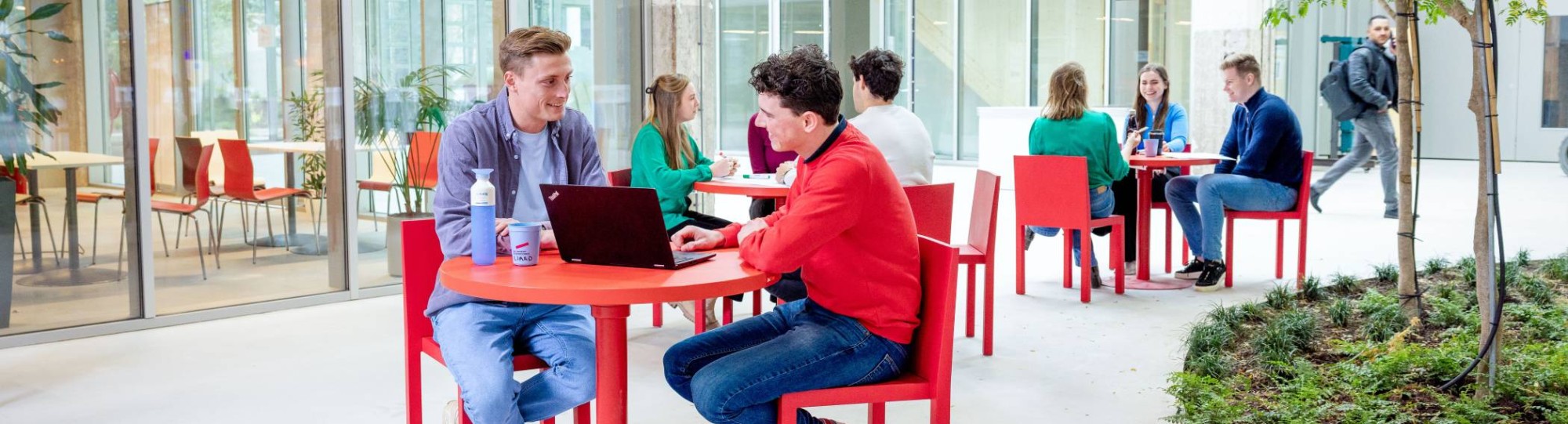 Locatieshot van IPKW met drie groepjes studenten aan tafel. Master Circulaire Economie 2024.