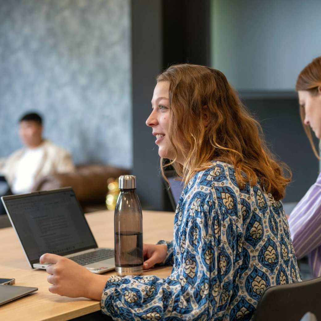 Student in een klas, overlegt met andere studenten, ze heeft plezier.
